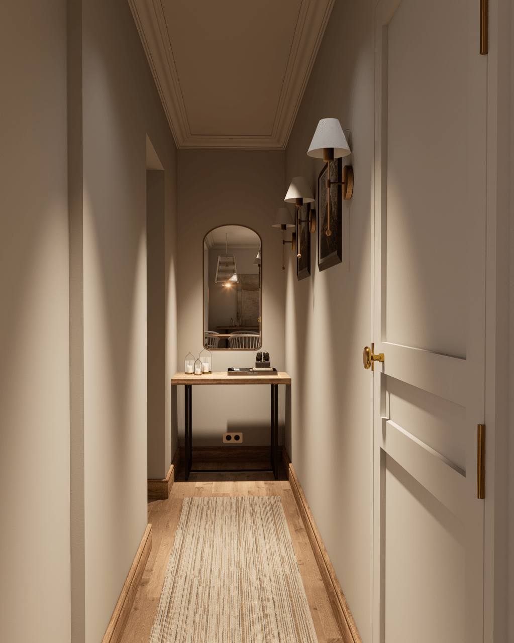 Long, narrow hallway with cream-colored walls and wooden flooring. Decorated with wall-mounted lamps, paintings, and a mirror, leading to a door with a golden handle. A rug runs along the floor.