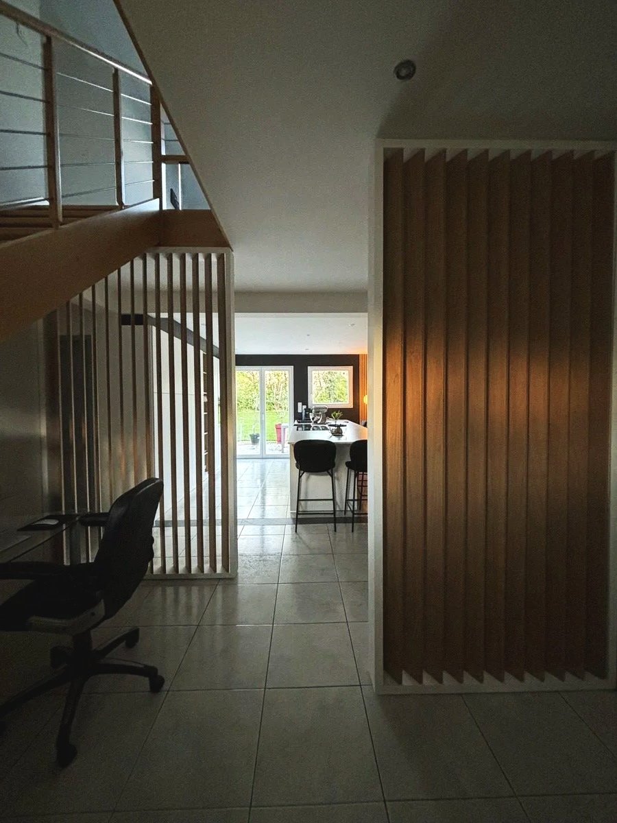 Entrée moderne rénovée dans la maison à charnay avec un espace cuisine et salle à manger lumineux, accès à un jardin extérieur via des portes en verre, claustra en bois et mobilier moderne.