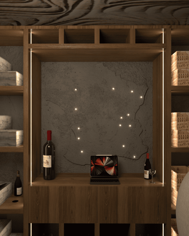 Une petite cave à vin avec deux fauteuils, une table en bois, des étagères remplies de caisses de vin, une carte de la France. Appartement haut de gamme rénové selon le thème du vin à Neuilly sur Seine.
