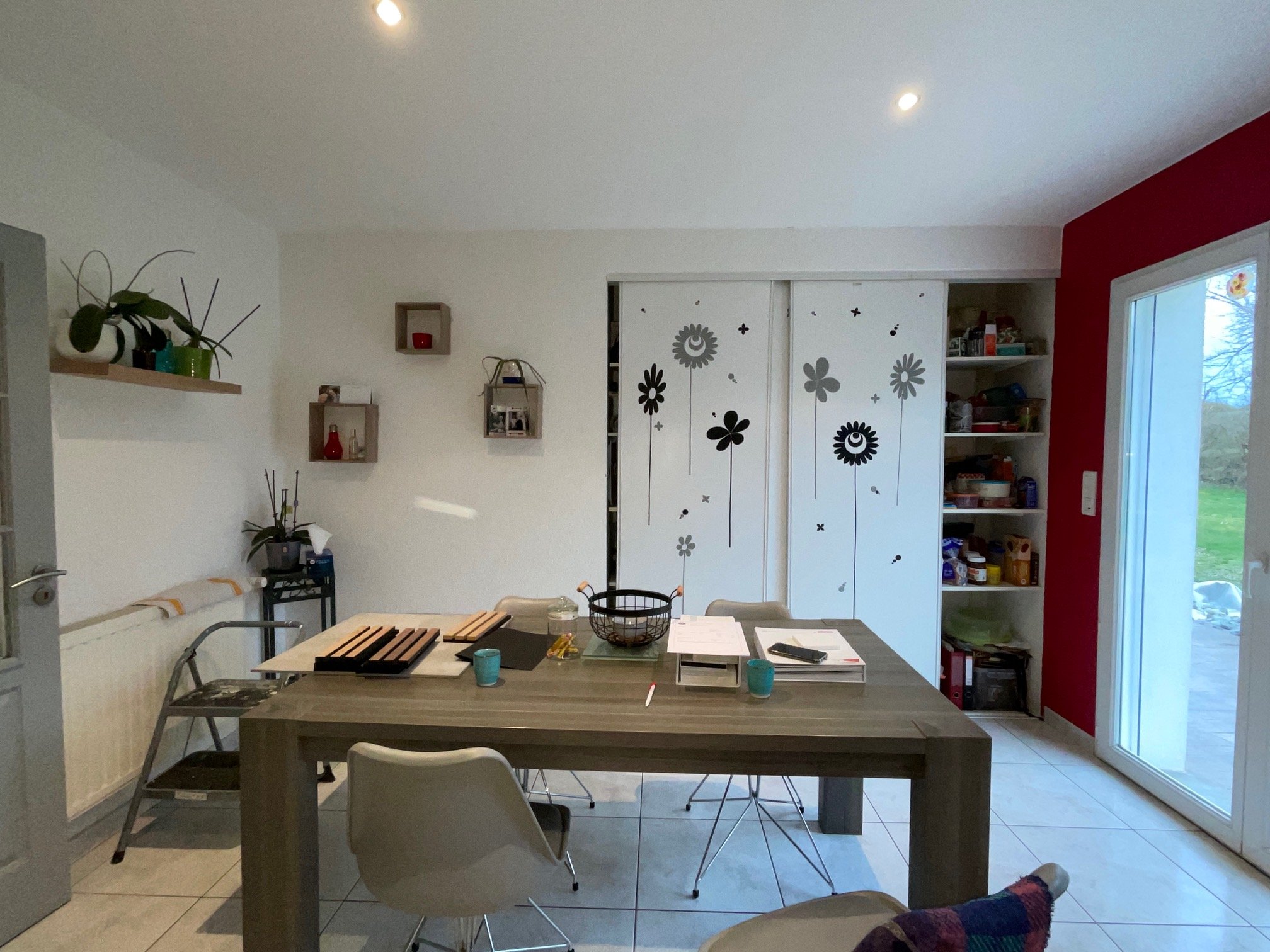 Cuisine existante de la maison rénovée à charnay avec murs rouges, armoires en bois, un plan de travail noir, deux fenêtres donnant sur un jardin et une porte-fenêtre.