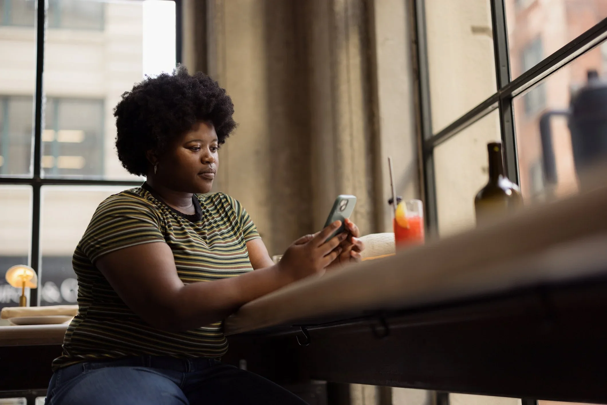 Young woman in a cafeteria while texting in her phone.