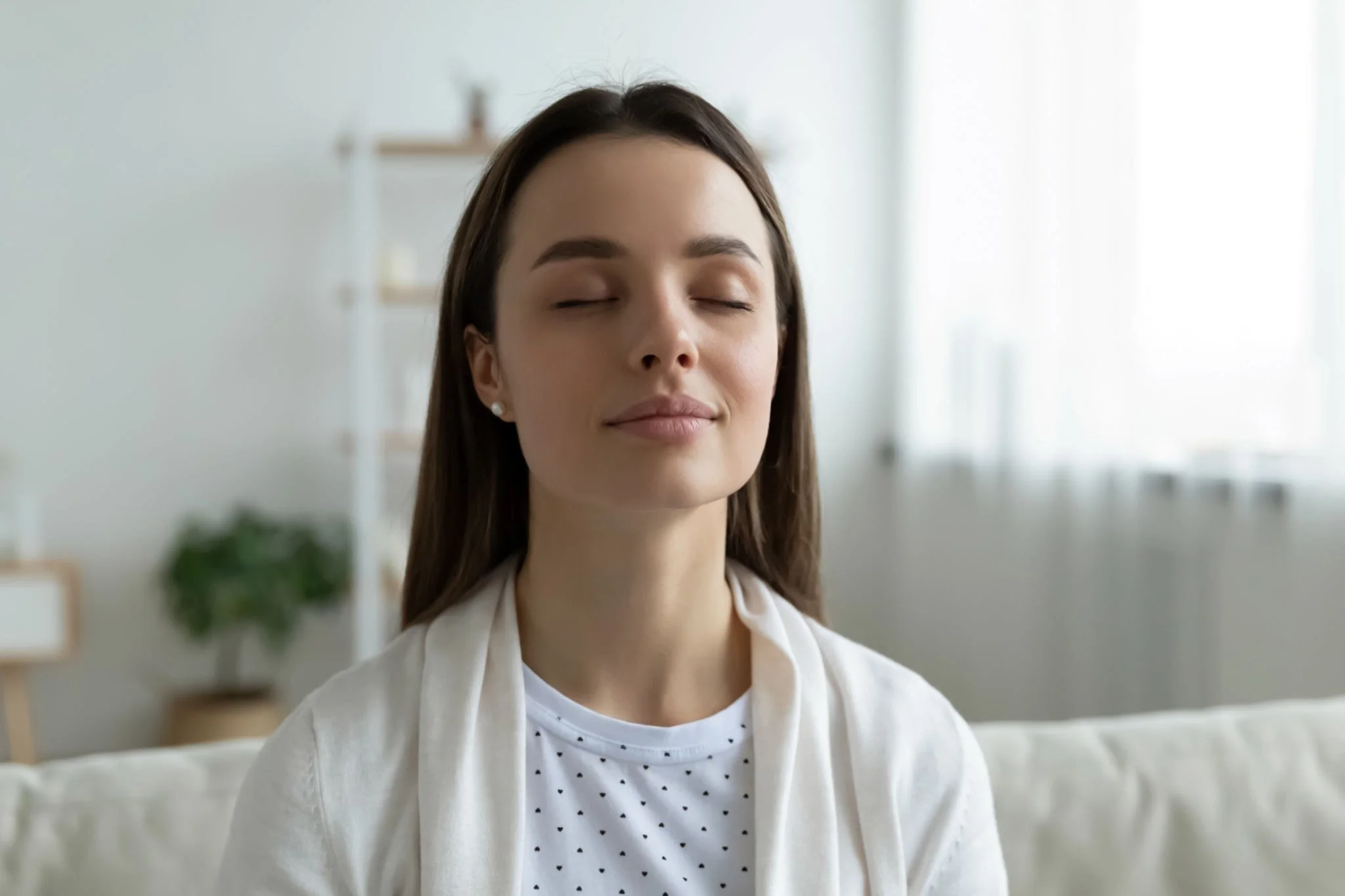 A woman sitting alone with her eyes closed, taking a peaceful breath
