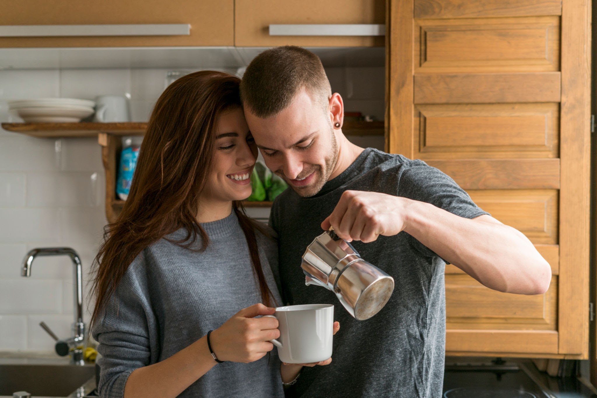 A couple calmly pouring coffee and talking in the kitchen