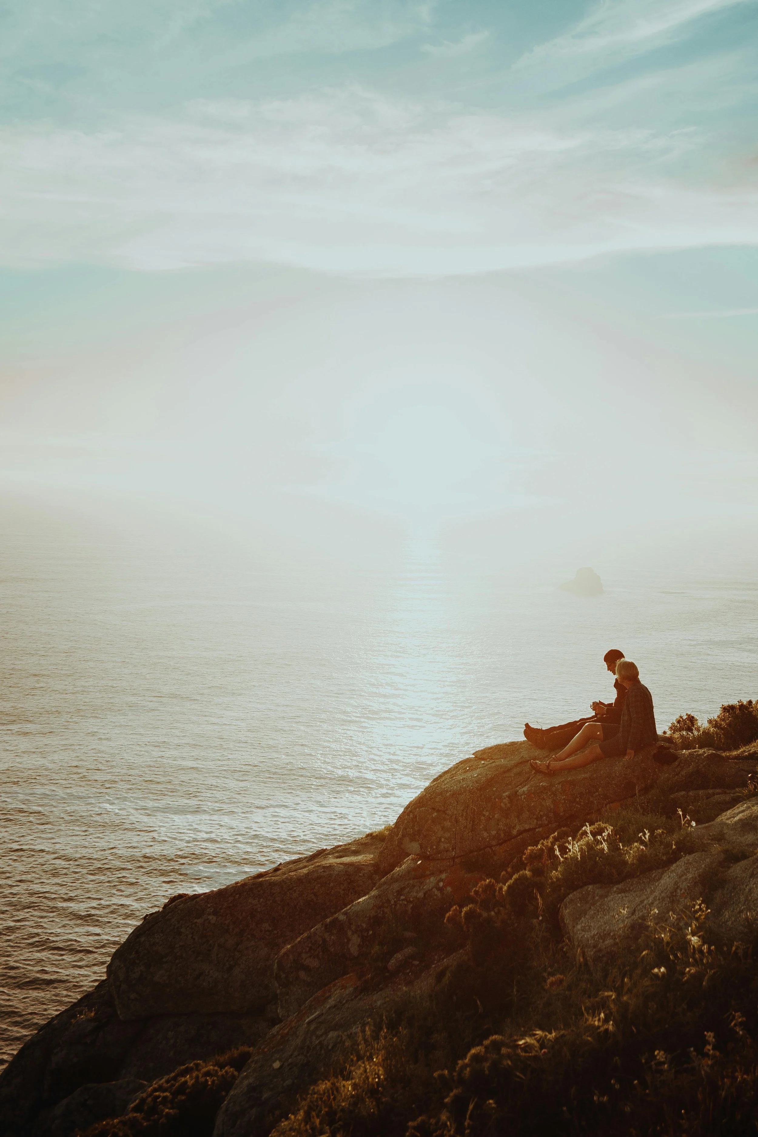 A couple sitting together looking out over the water in the Pacific Northwest, representing the grounded, relational healing offered through modern therapy at Made Whole Counseling.