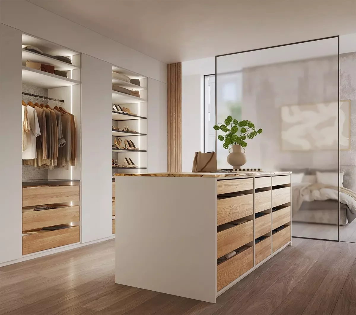 Modern walk-in closet with built-in shelving, hanging clothes, shoes, and a central wooden dresser. A glass partition separates a bedroom with a bed and abstract artwork, and a window lets in natural light.