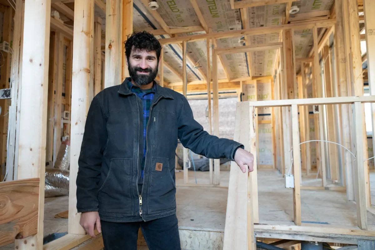 Azad Lassiter, founder of High-Performance Builders of Minnesota, standing inside a home under construction surrounded by wood framing.
