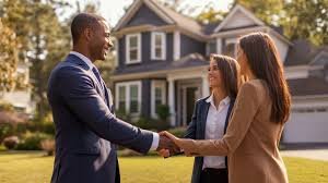 A man and two women shaking hands outdoors in front of a house.