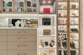 A walk-in closet with shelves of shoes, a laundry area with a countertop, and drawers for storage.