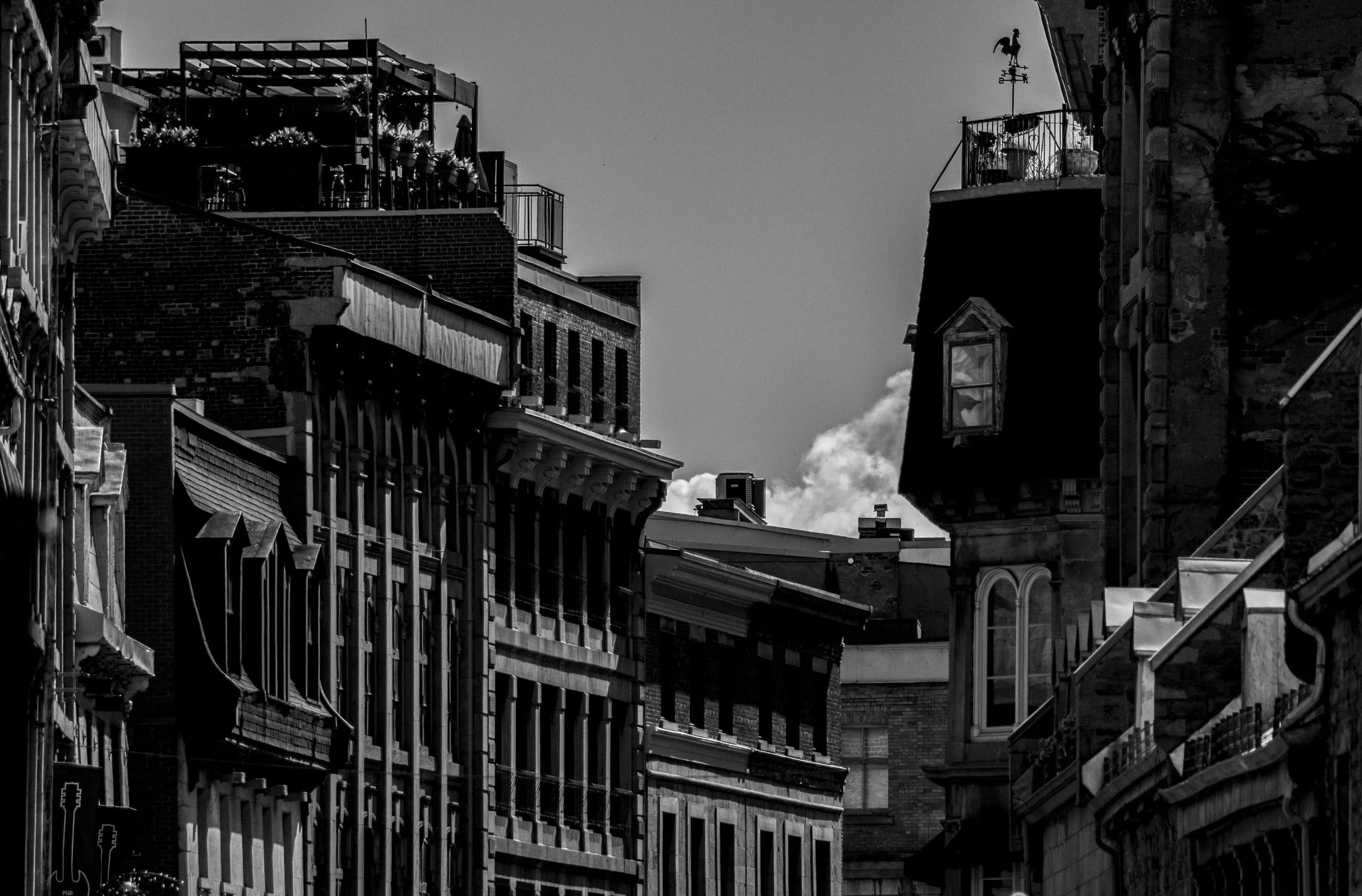 Immeubles anciens et modernes avec toits en ardoise et balcons, vue urbaine en noir et blanc