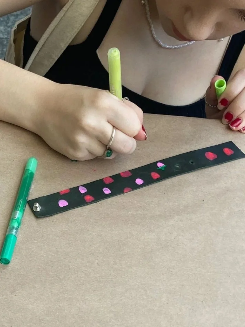 Person decorating an upcycled leather bracelet at a Kiki Knows Art workshop.