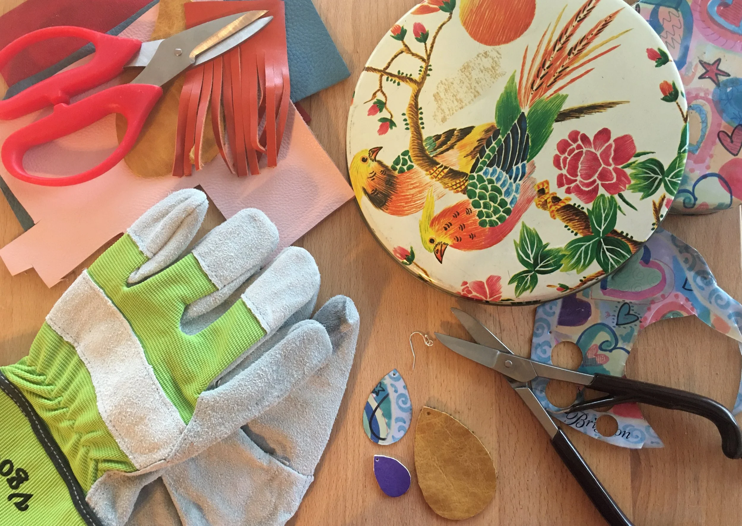Tools used at a Kiki Knows Art workshop including gloves, scissors, pliers, and colorful upcycled materials.