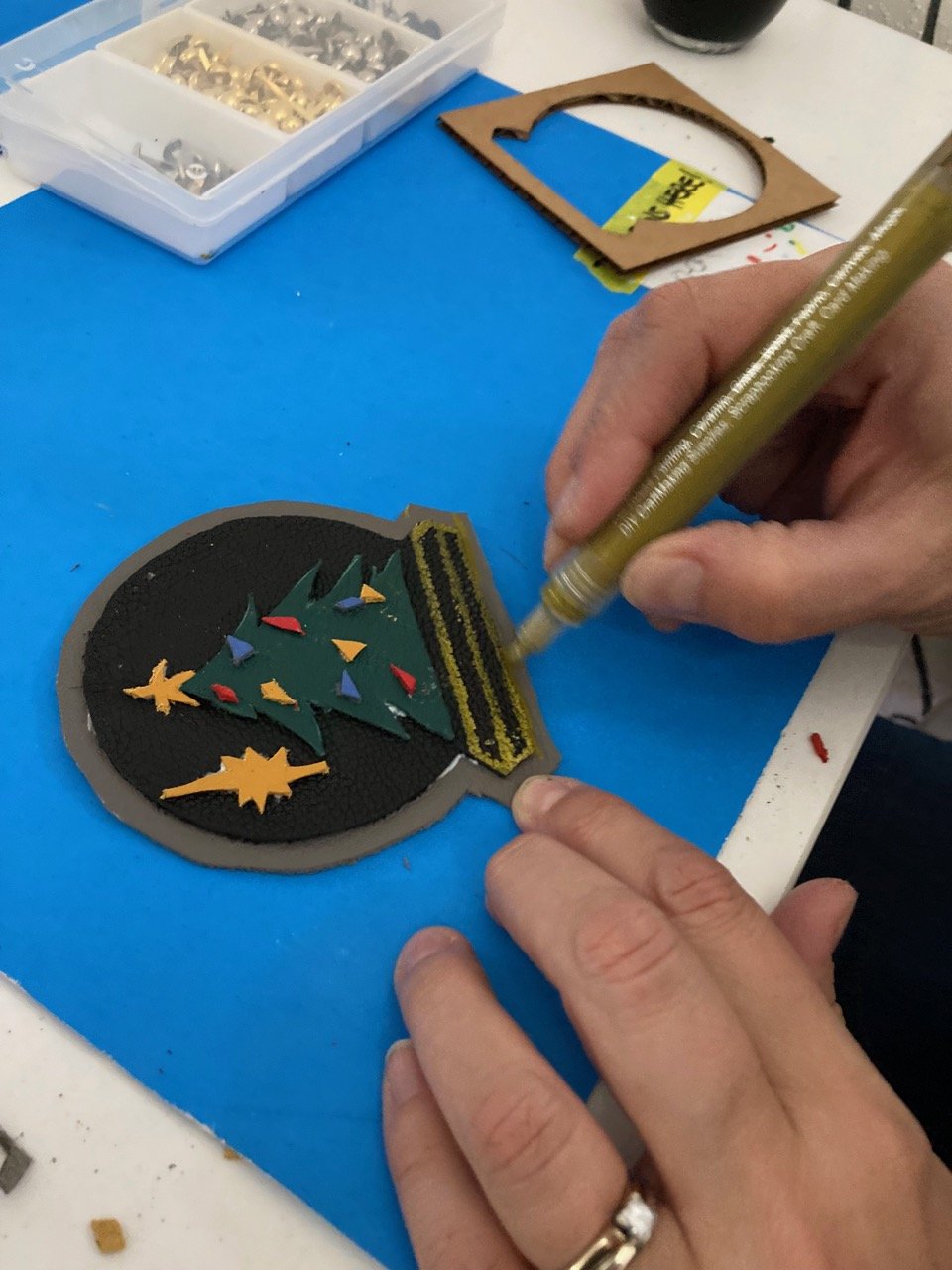 Person creating a Christmas tree ornament at a Kiki Knows Art workshop.