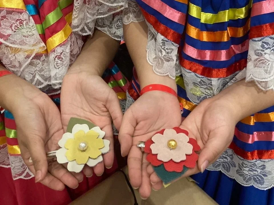 A pair of hands holding colorful floral hair clips made at a Kiki Knows Art workshop.