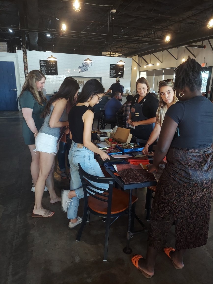 Carolyn Marco teaching a Kiki Knows Art leather craft workshop with a group of young women.
