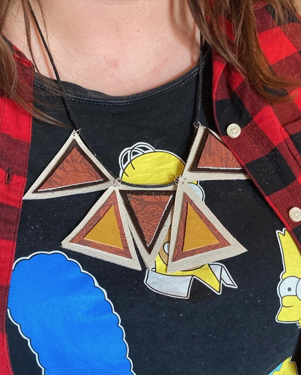 Person wearing an upcycled leather necklace made of triangular shapes.