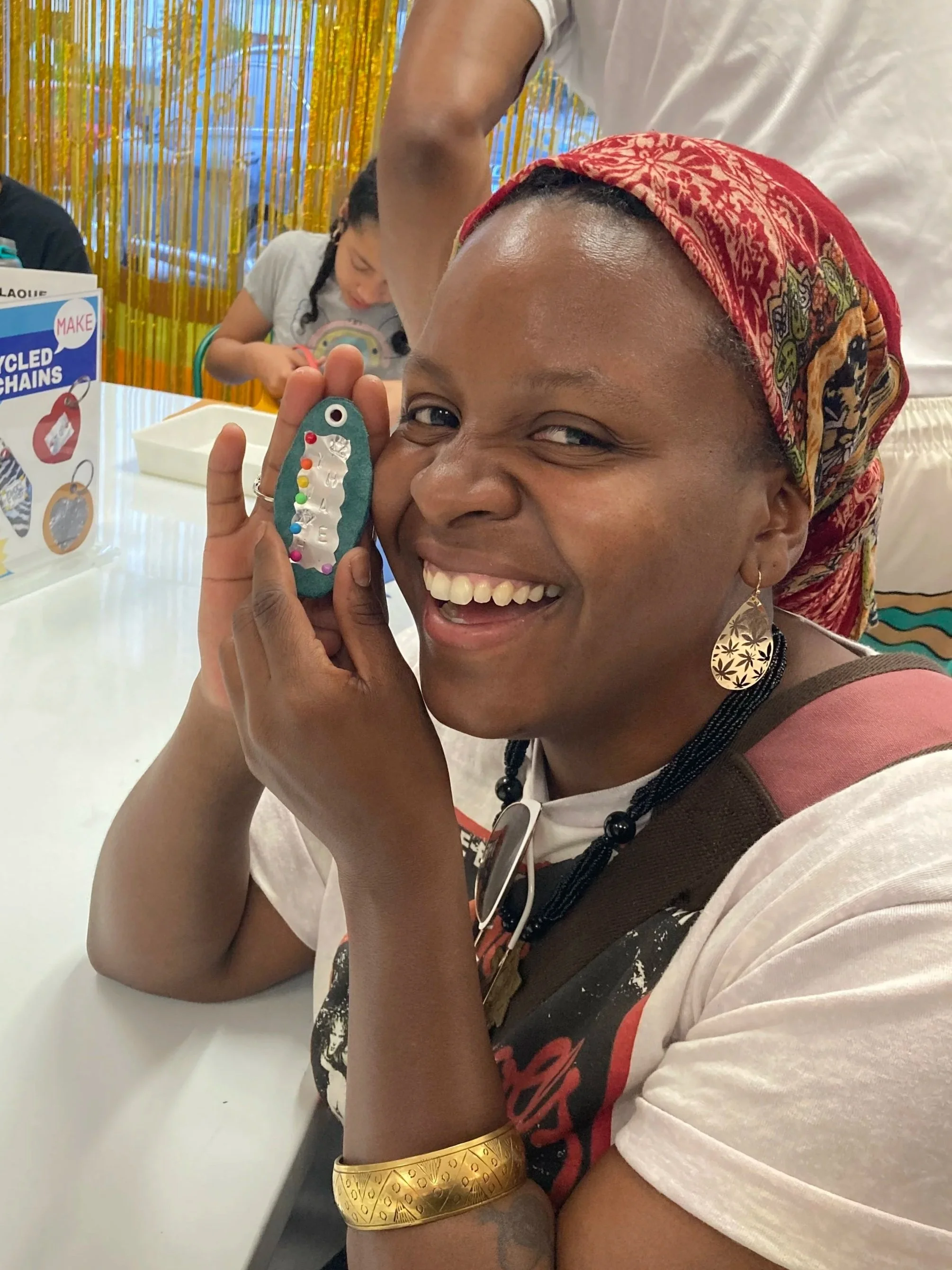 Person smiling and holding a personalized keychain made at a Kiki Knows Art workshop.