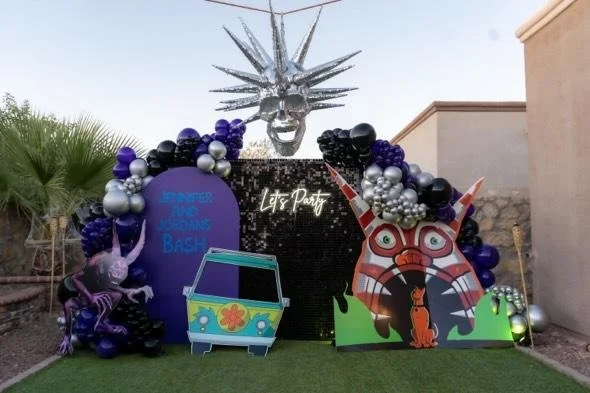 Decorative jungle-themed party setup with balloons, a silver head sculpture, and colorful animal cutouts, including a large tiger face and purple dragons.