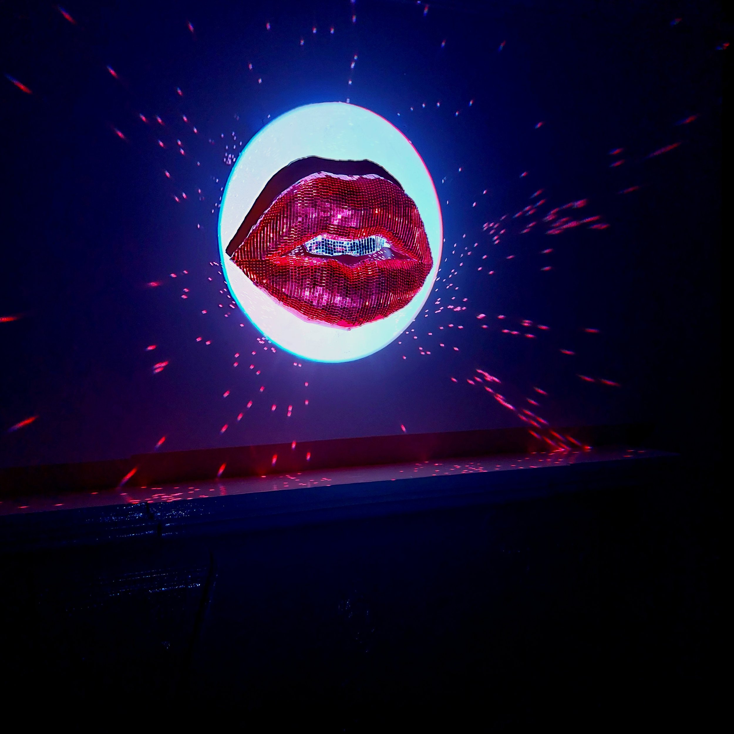 A digital art display of a face with red lips, illuminated against a dark background with red and blue light effects.
