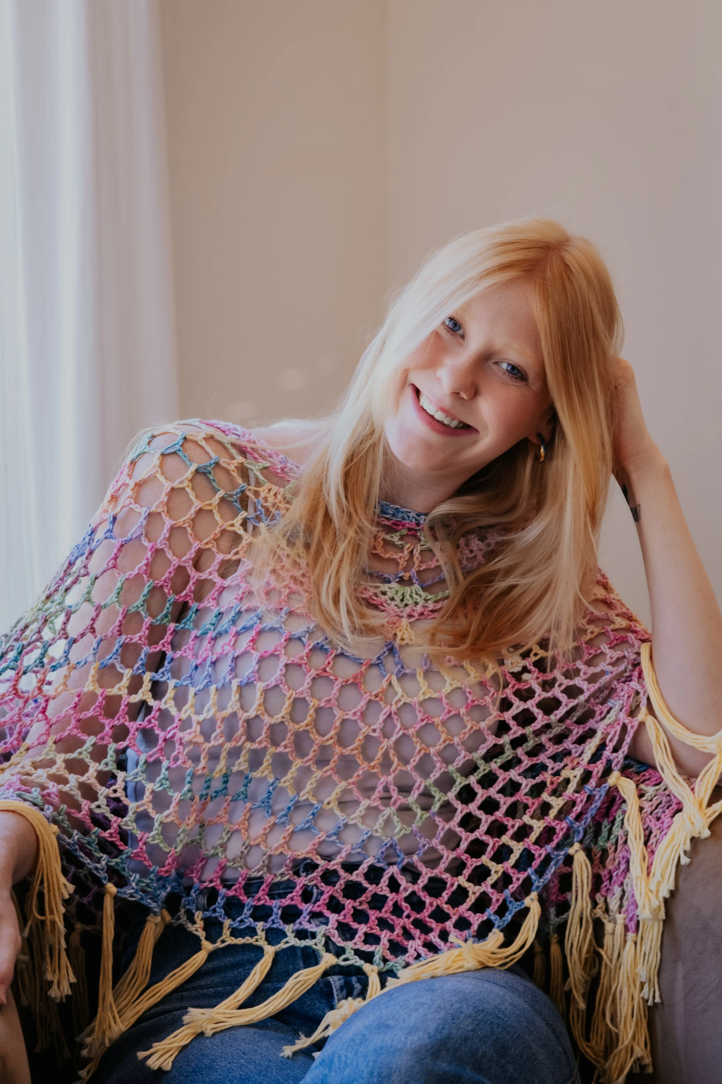 Maggie wearing a handmade pastel crochet poncho with yellow fringe