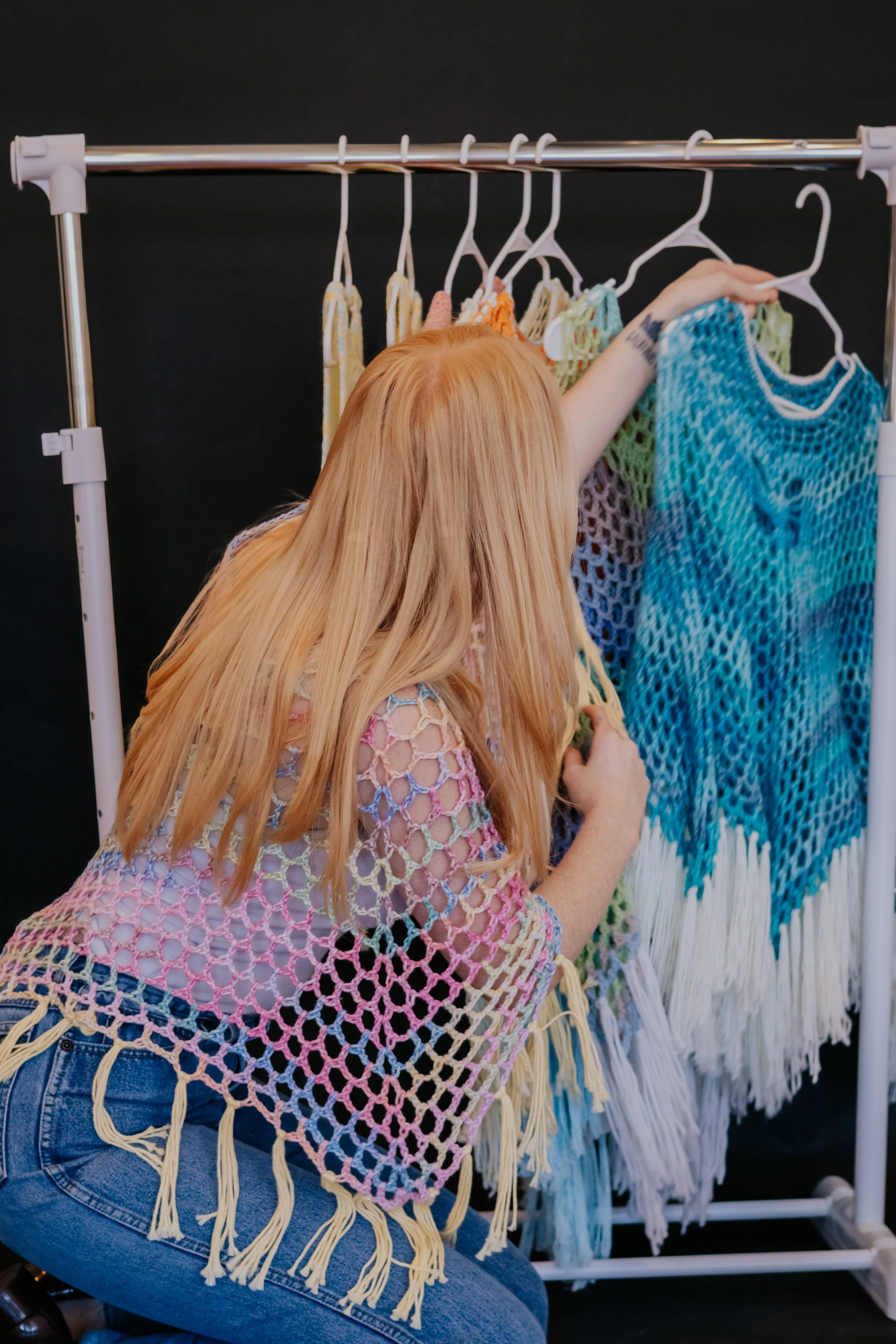Blue and white crochet Solace Ponchos on a garment rack