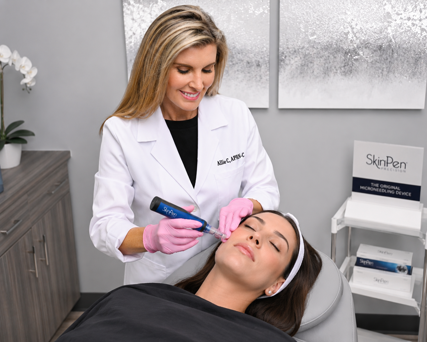 A woman lying with eyes closed on a cosmetic treatment chair, receiving a facial injection from a female healthcare professional, in a modern clinic setting.