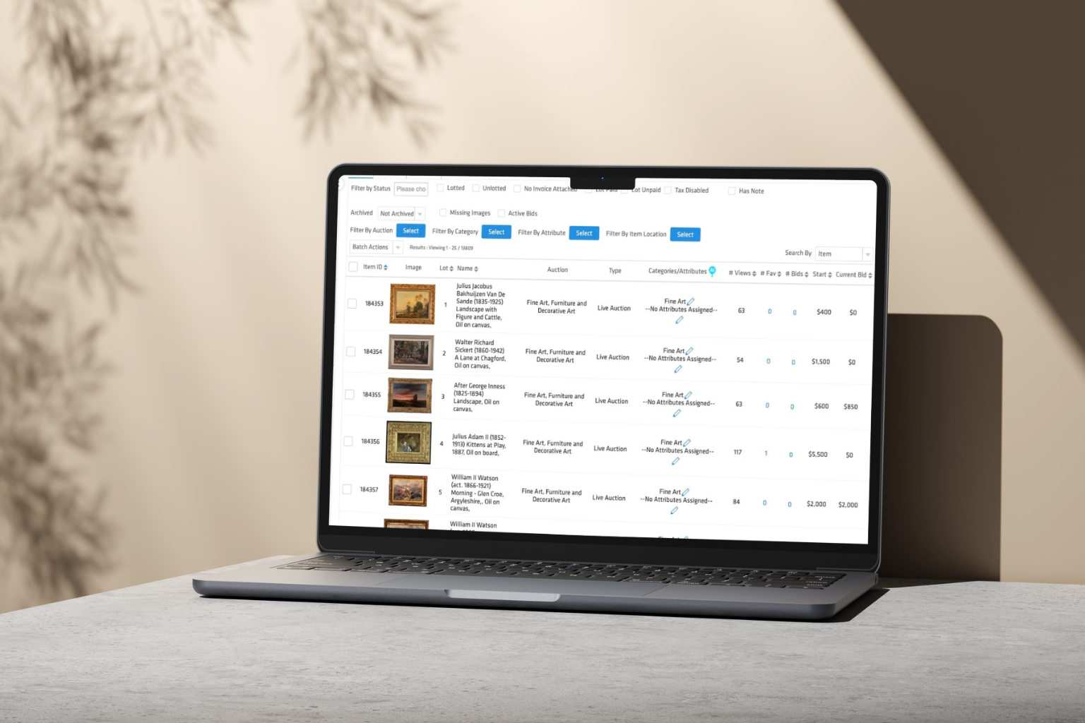 Laptop displaying an online auction management dashboard with listed fine art paintings, bids, and sale prices.