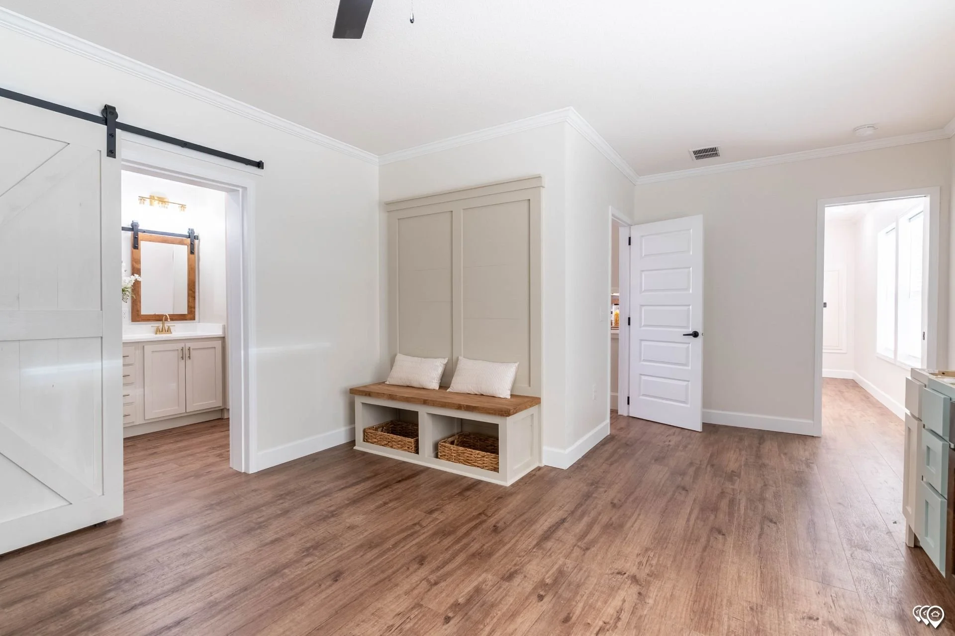 Interior of a modern home with hardwood floors, white walls, and multiple open doors leading to different rooms.