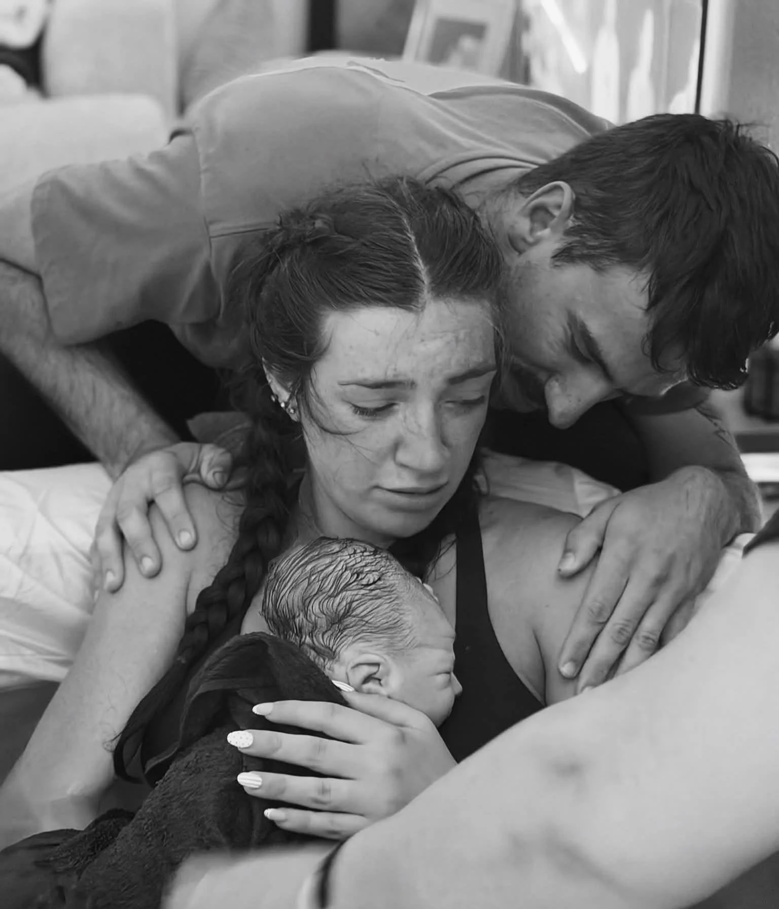 A group of people, including a woman and two children, are embracing each other emotionally, possibly in a moment of comfort or joy. The scene appears to be candid and intimate.