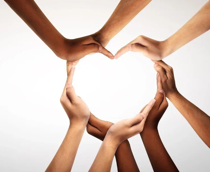 Multiple hands of different skin tones forming the shape of a heart.