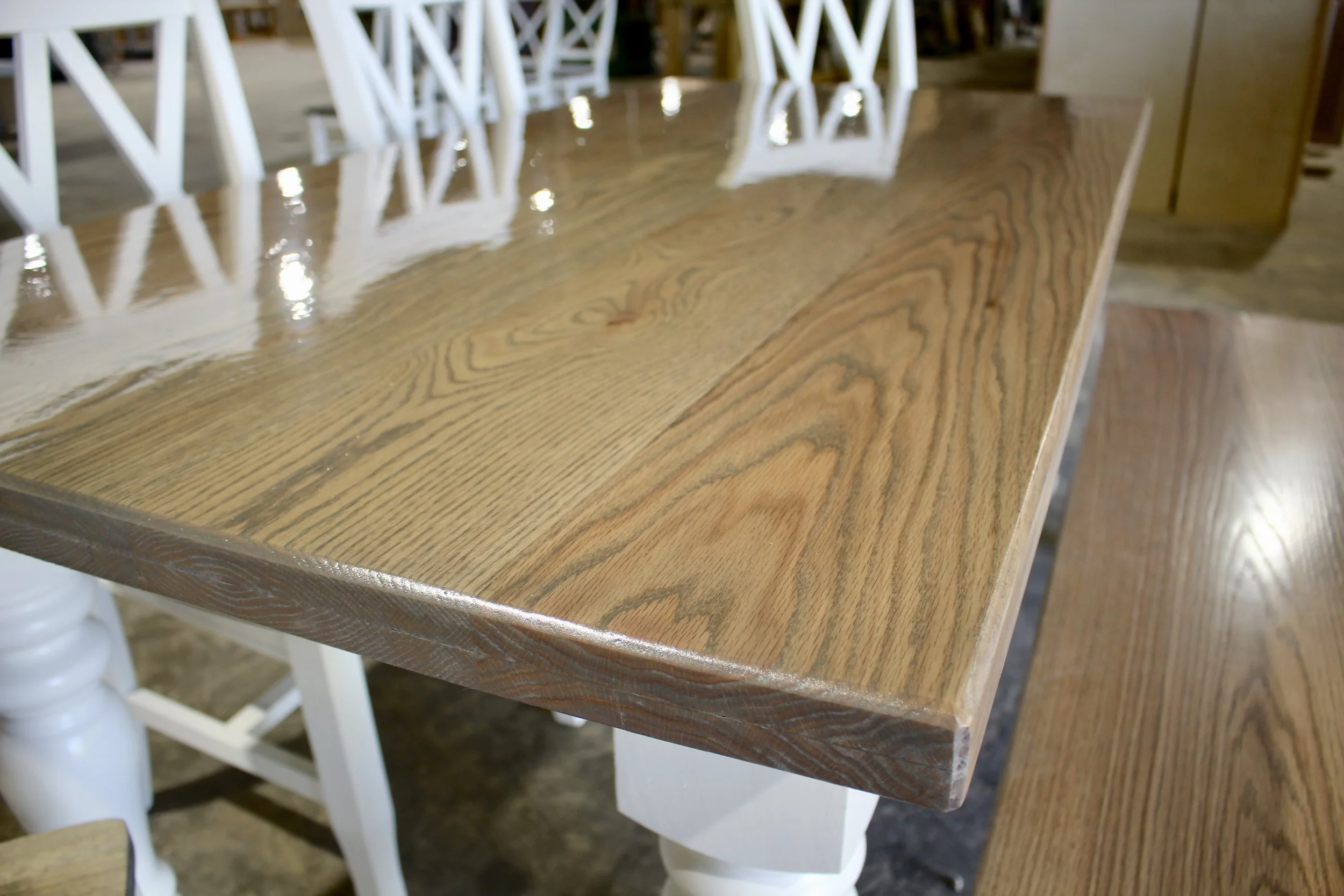 A wooden dining table with a glossy finish and white chairs in a furniture store.