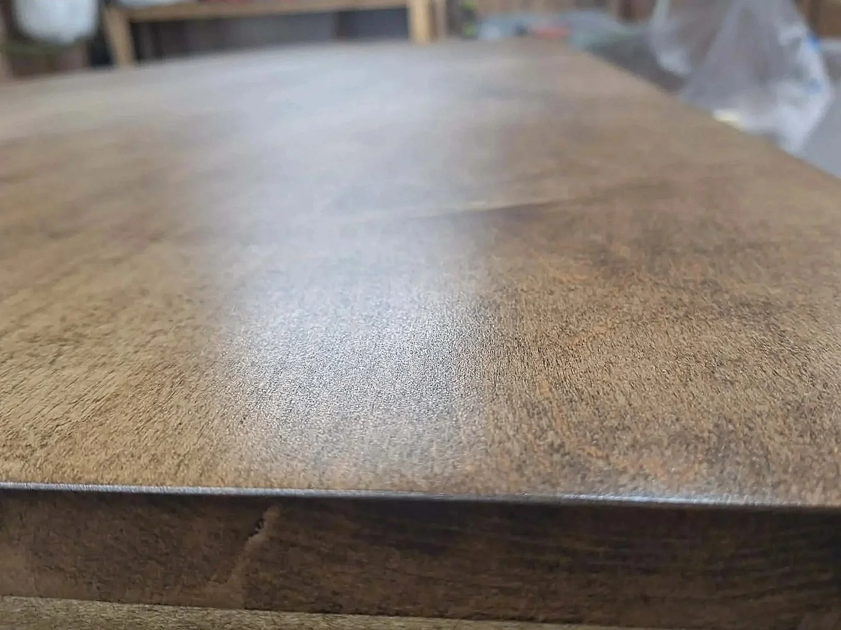 Close-up of a wooden table surface with a visible grain pattern and smooth finish.