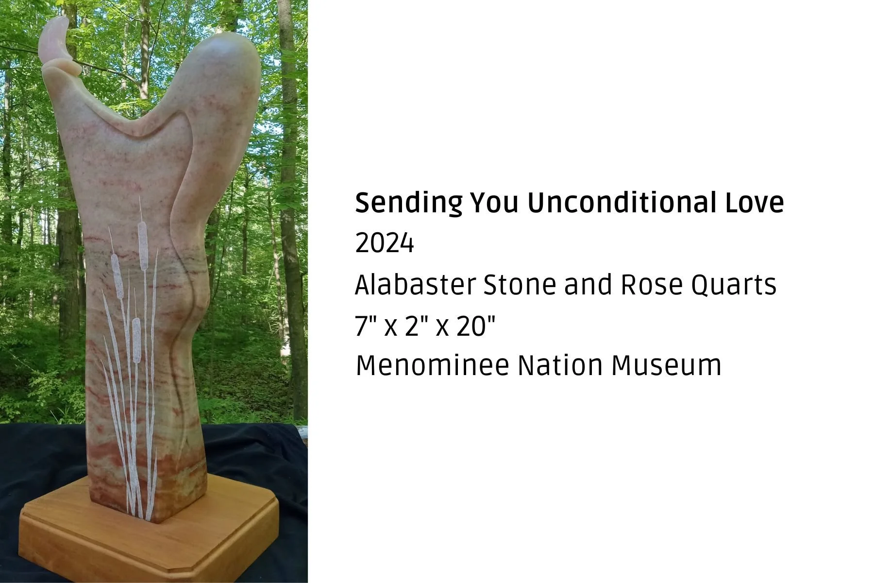 A carved alabaster stone sculpture resembling a tall, abstract hand with delicate white inlay flowers at the base, displayed on a wooden pedestal against a forest background.