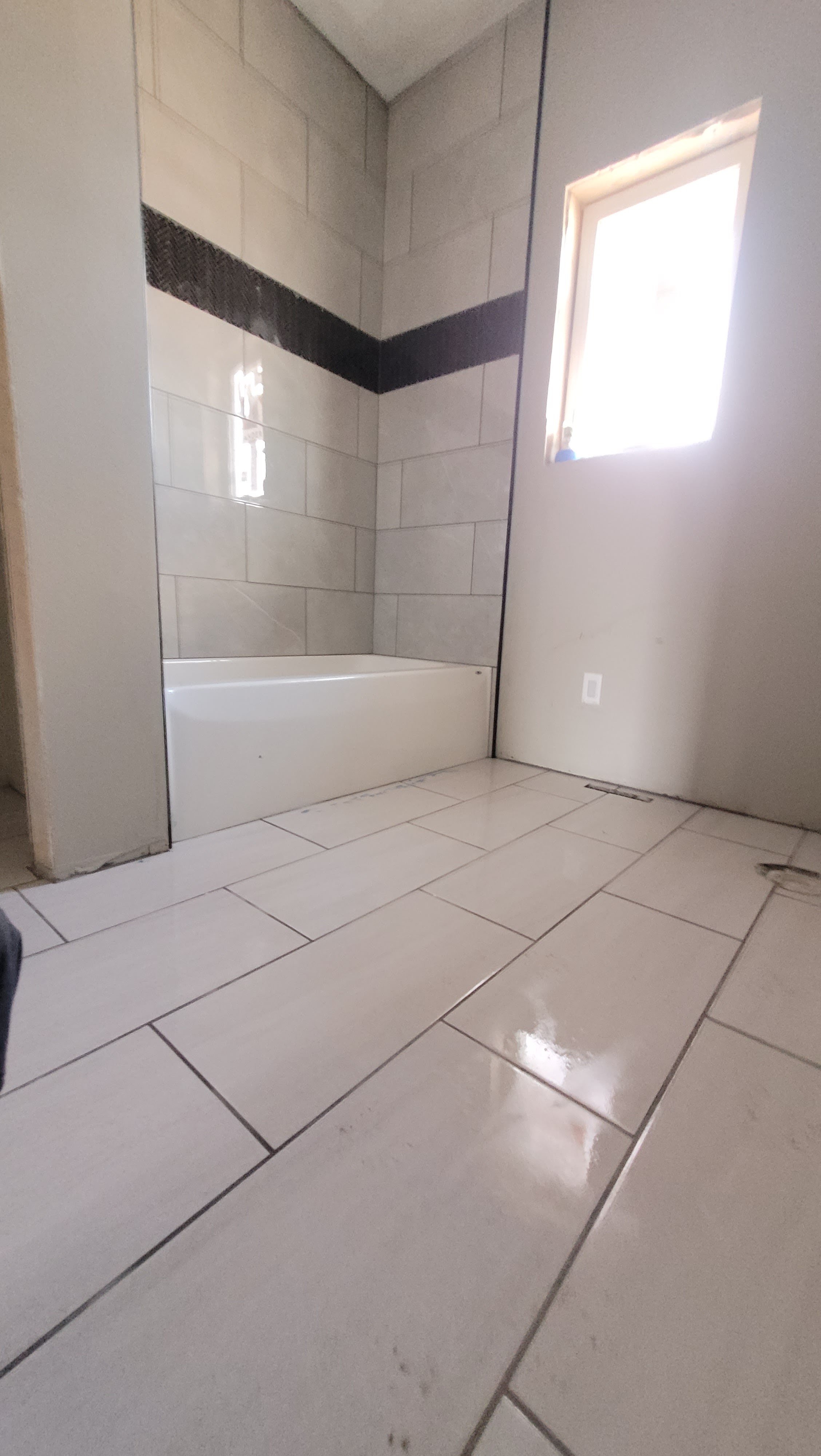 Ceramic tile bathroom remodel featuring white subway tile and dark accent strip