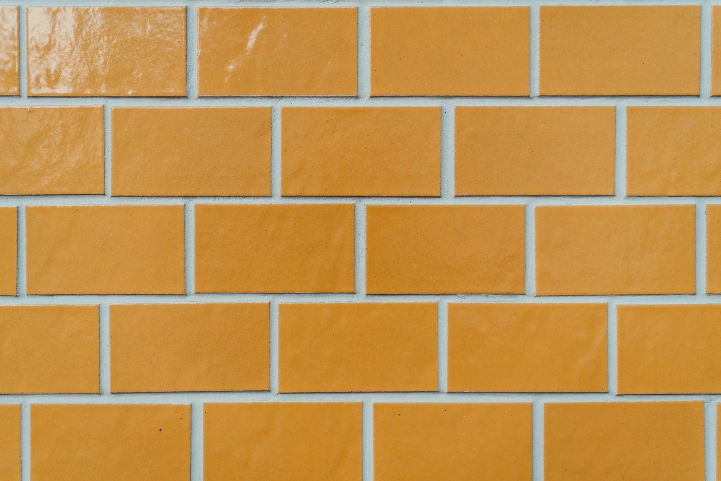 Close-up of a brick wall with orange bricks and white mortar lines.