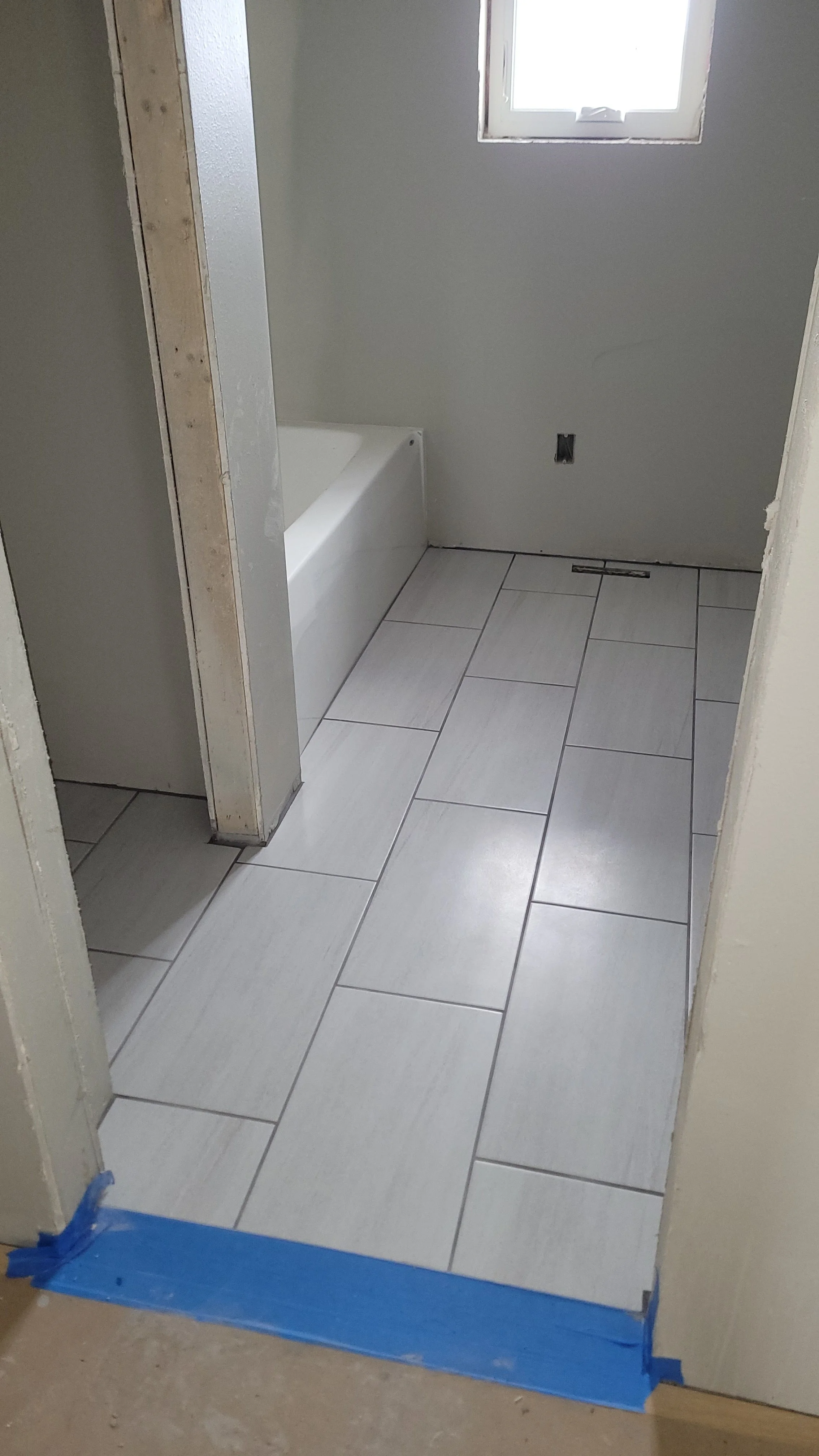 New white ceramic tile floor installation in bathroom renovation