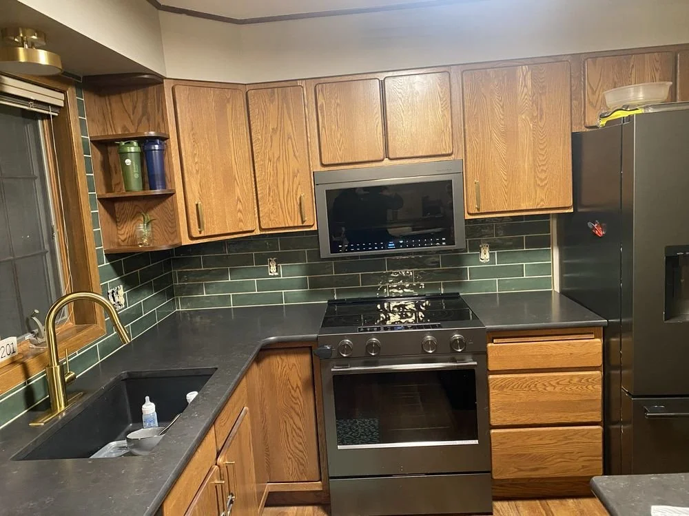Kitchen featuring green subway tile backsplash, dark countertops, and wood cabinets