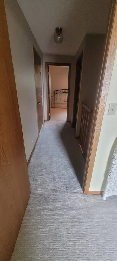 Long residential hallway with soft gray carpet tiles installed