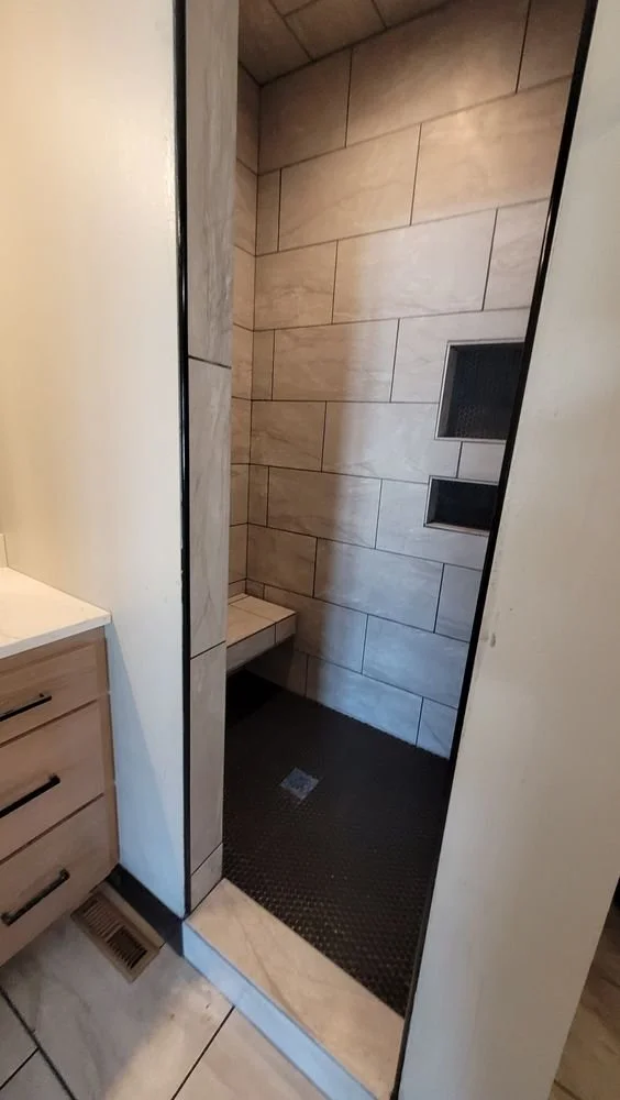 Modern tiled shower with built-in bench and beige ceramic tiles.