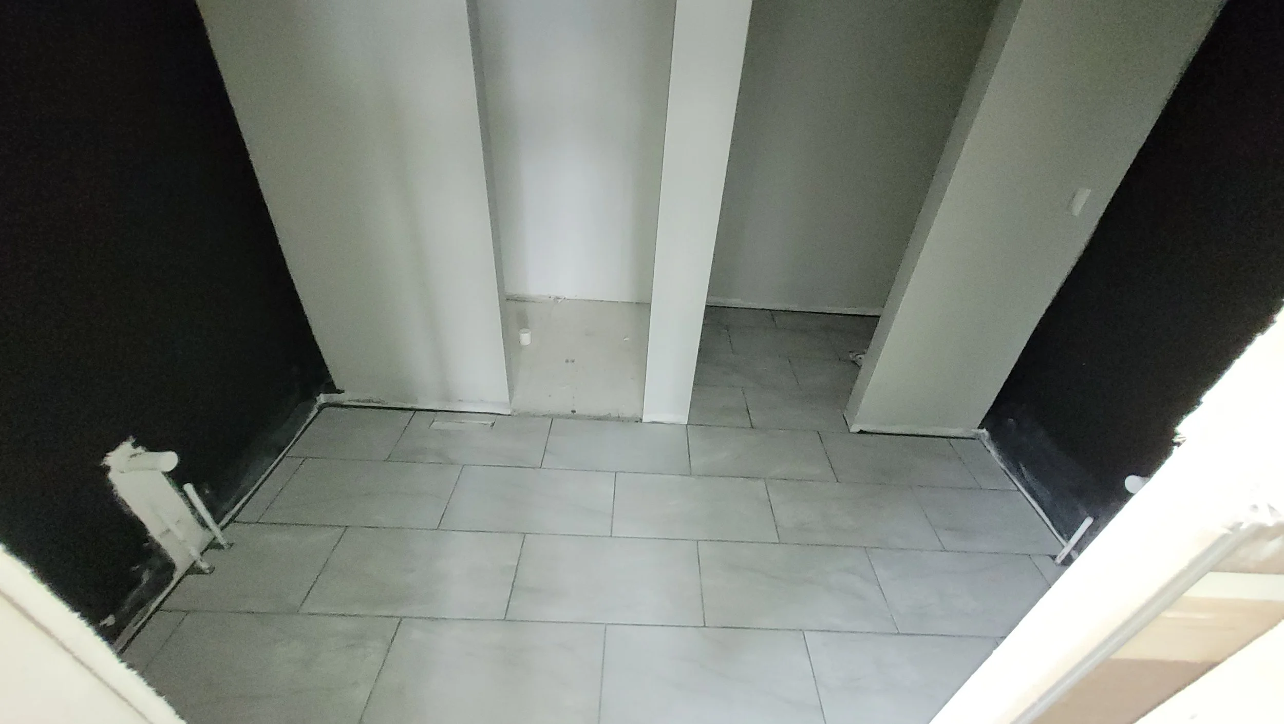 Large format gray ceramic tile floor installation in new construction room