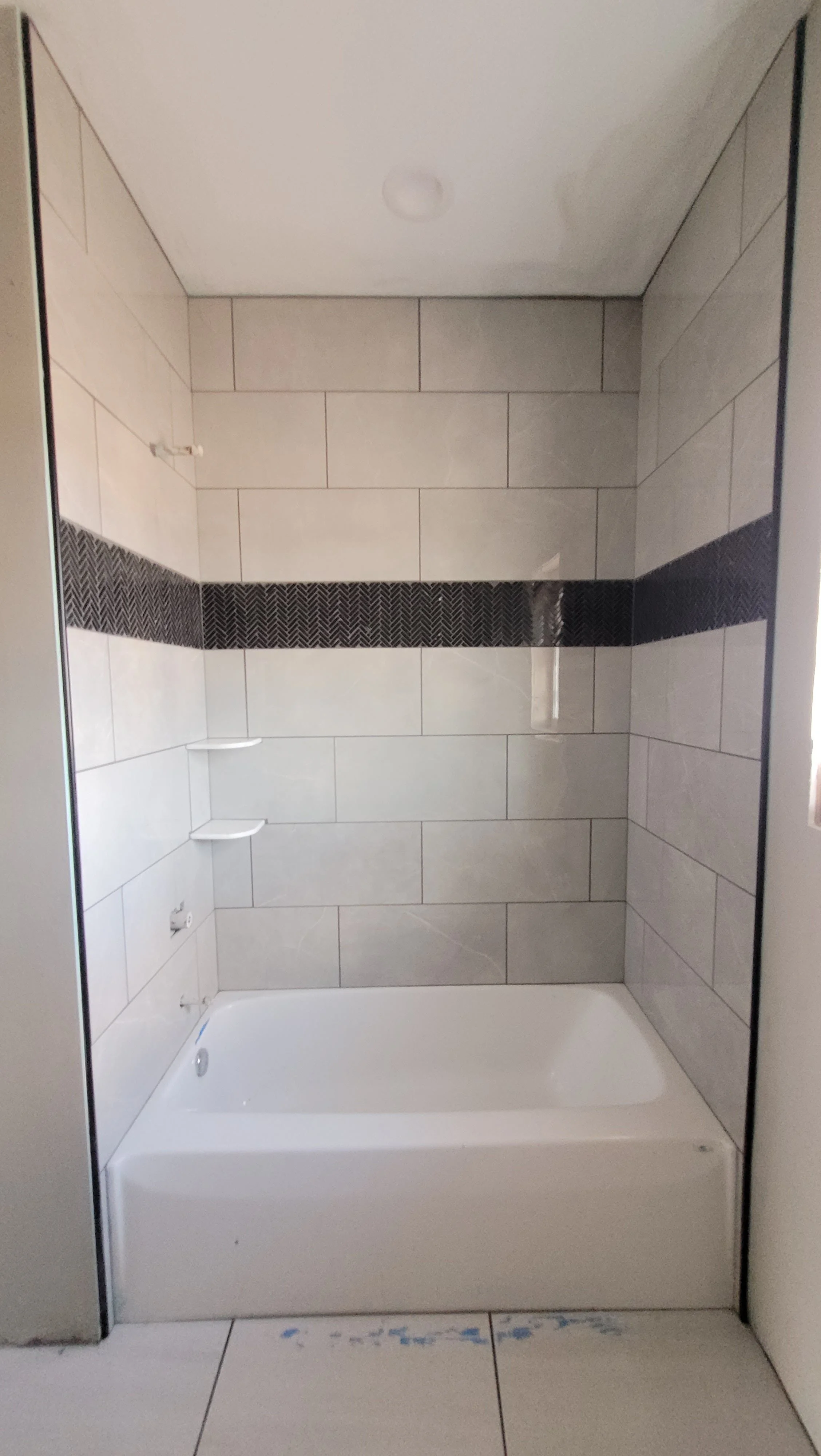 Modern bathroom with large format white ceramic wall tile and bathtub surround