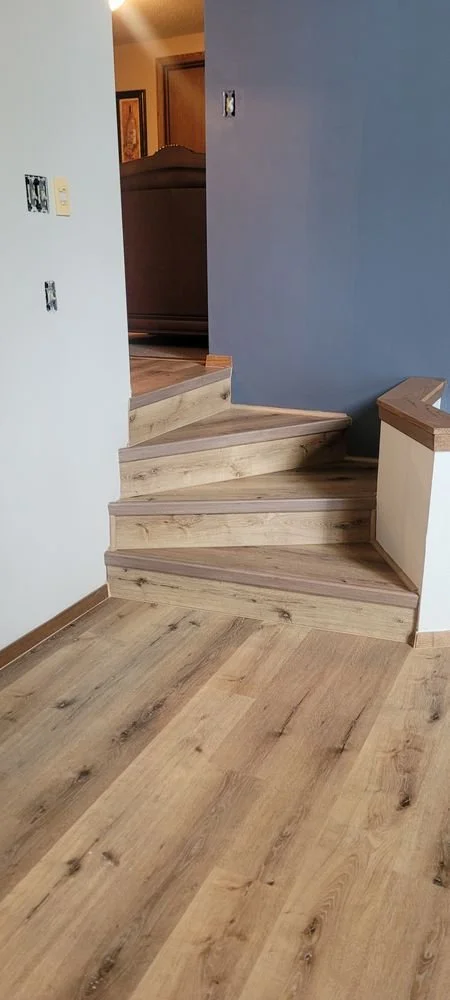 New luxury vinyl plank flooring installed at base of modern wood staircase