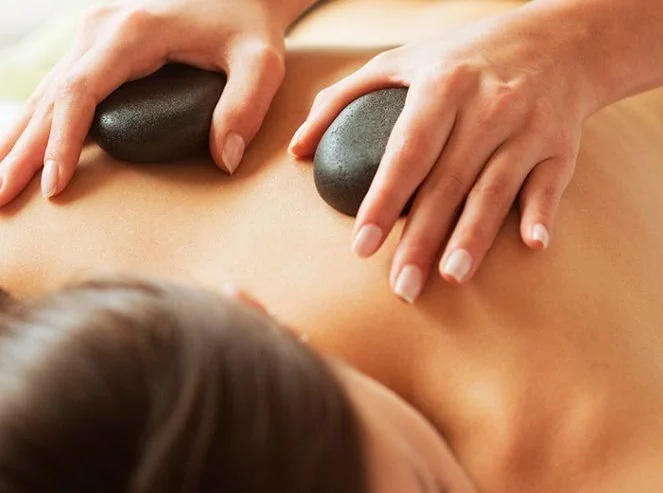 Person receiving hot stone massage on back, stones placed on the back during massage.