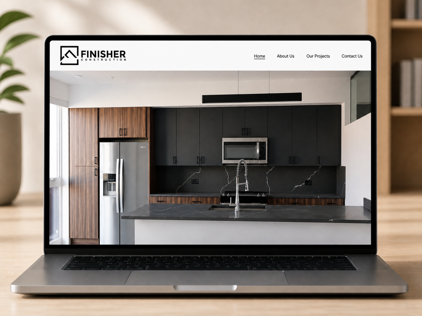 Laptop displaying a website for a construction company, showing a modern kitchen with black and wood cabinets, a black marble countertop, and stainless steel appliances.