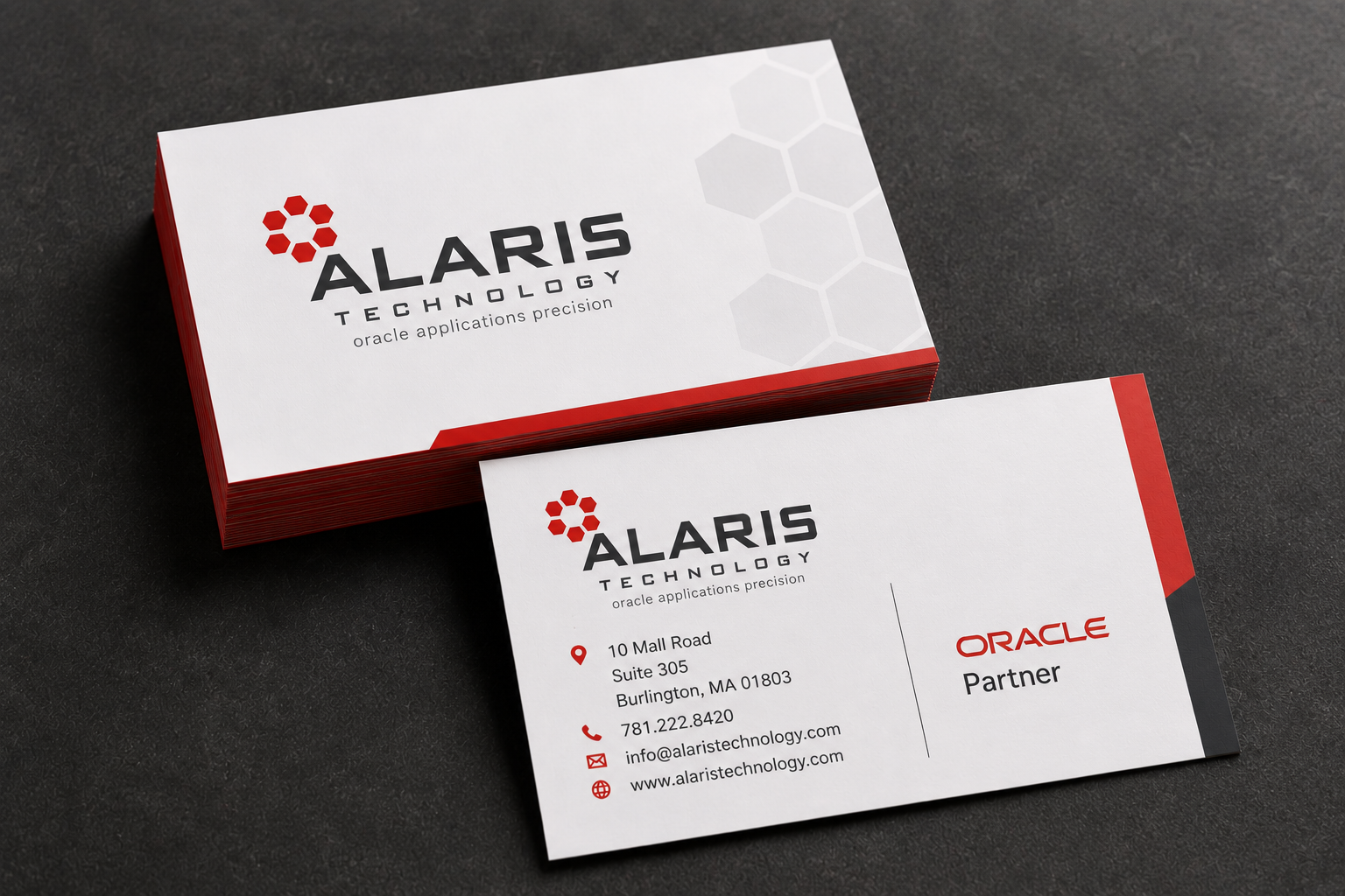 Business cards for Alaris Technology, displaying company logo, address, phone number, email, website, and indicating Oracle partnership, on a dark surface.