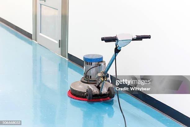 Floor cleaning machine on a shiny blue floor near a door.