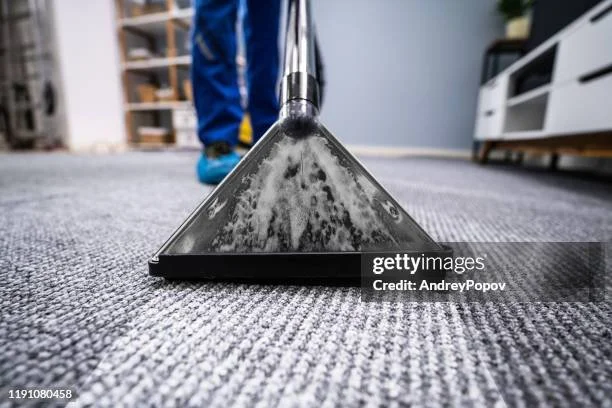 Close-up of a vacuum cleaner in action on a carpeted floor.