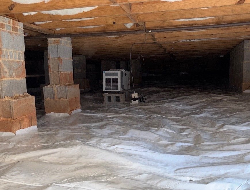 Attic space with insulation and a portable air conditioner.