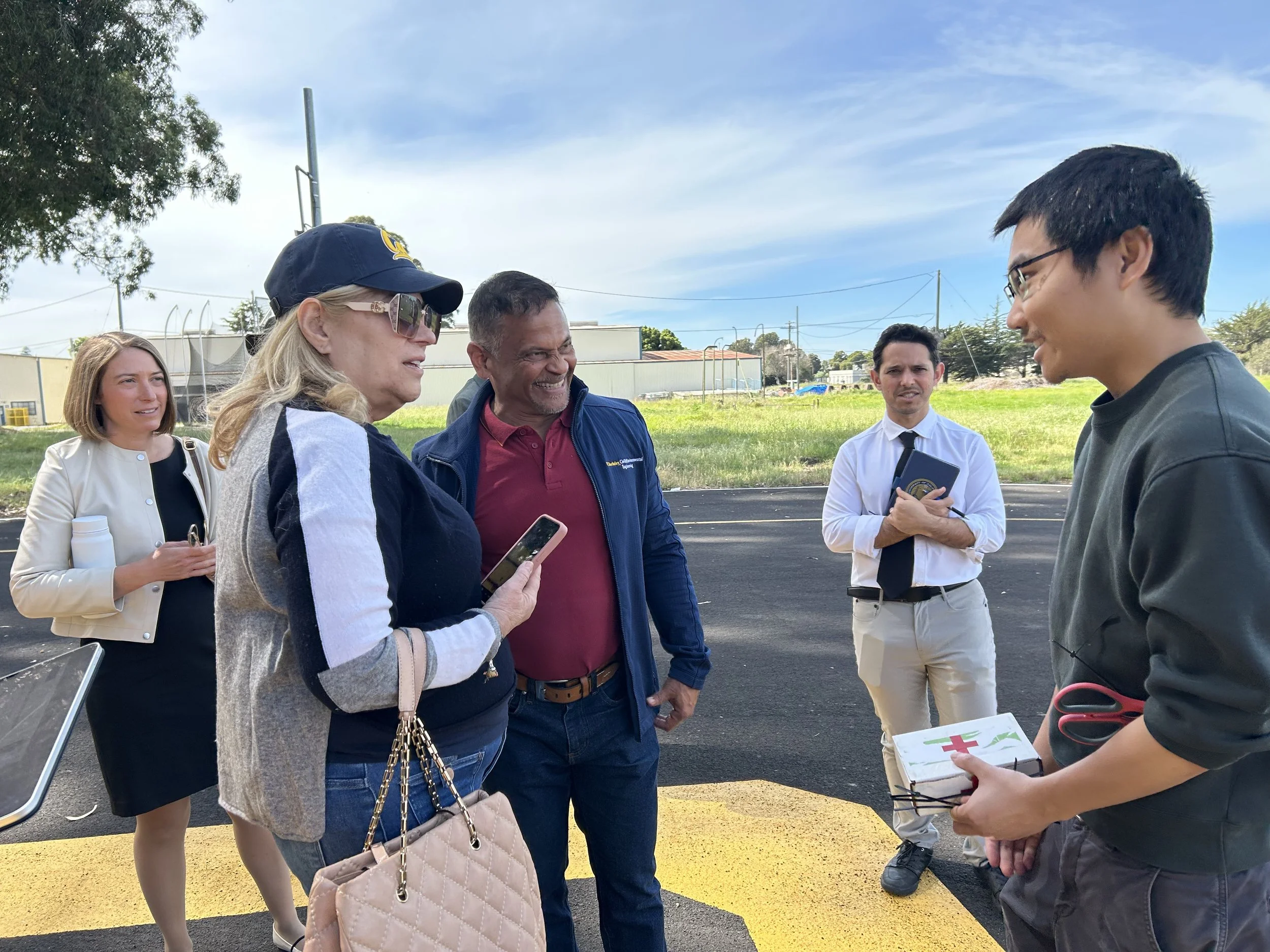 Seval Oz speaking to someone holding a first aid kit with people in the background