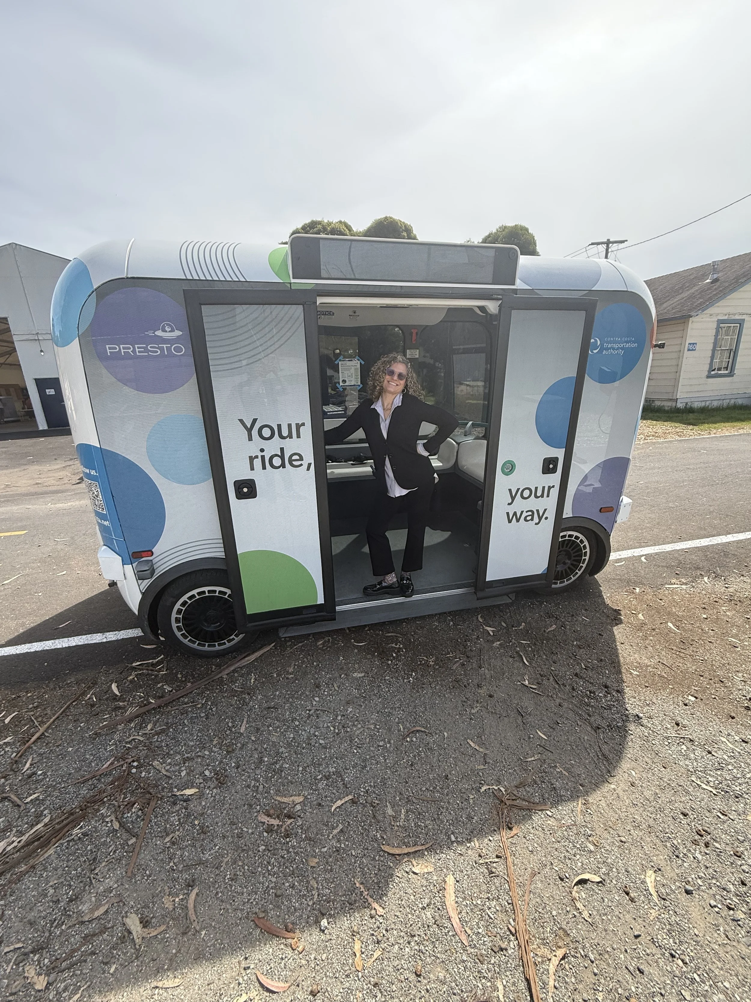 A woman in a black suit striking a pose inside an autonomous vehicle