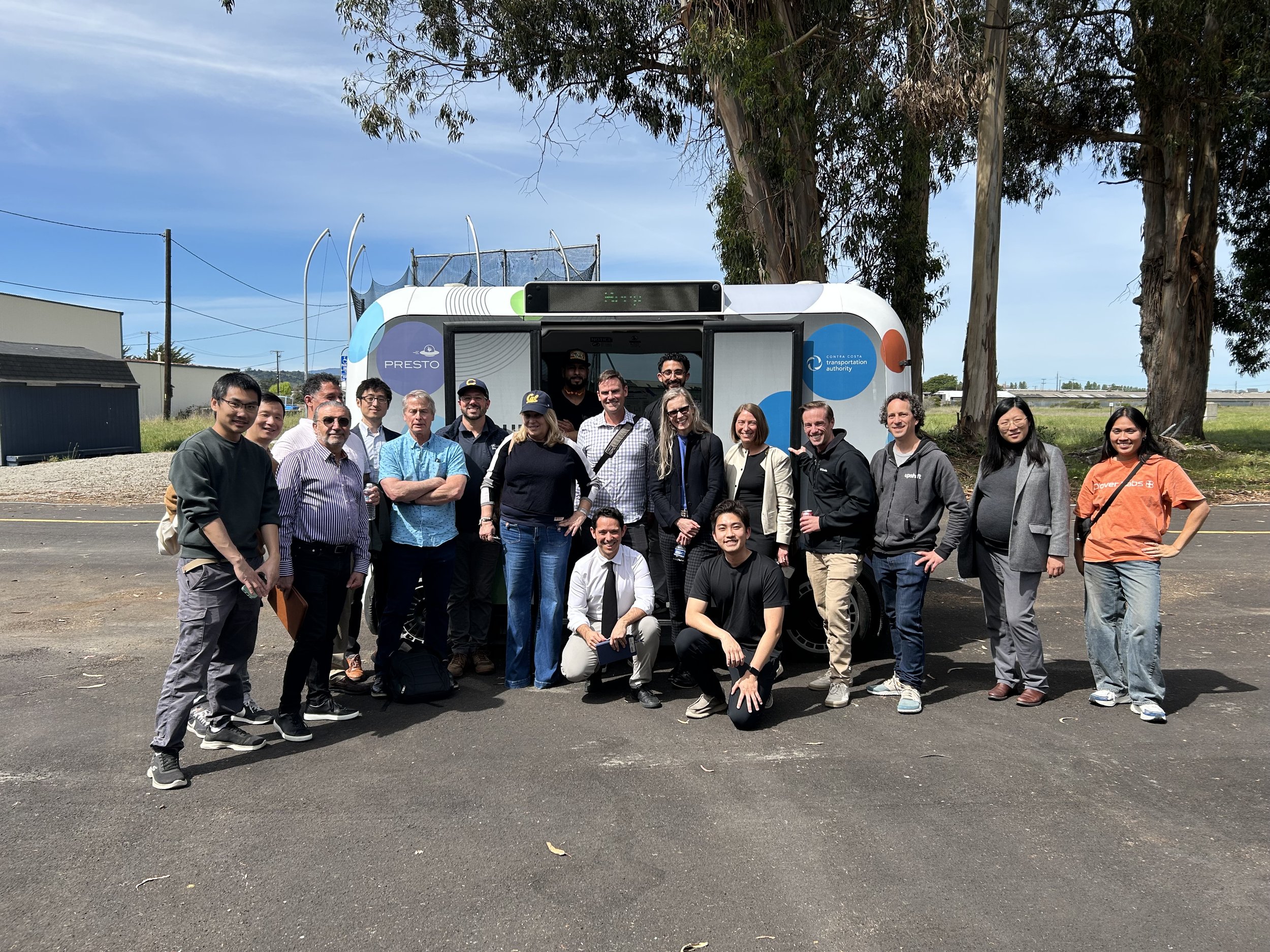 Group photo of people in front of an autonomous vehicle